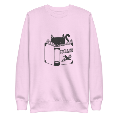 A black and white illustration features a cat peeking over an open book titled 'How to Kill a Mockingbird,' playfully altering the classic novel's title. The cat has a heart-shaped nose and simple, cute facial features. The design is whimsical and ironic, combining classic literature with a humorous twist.