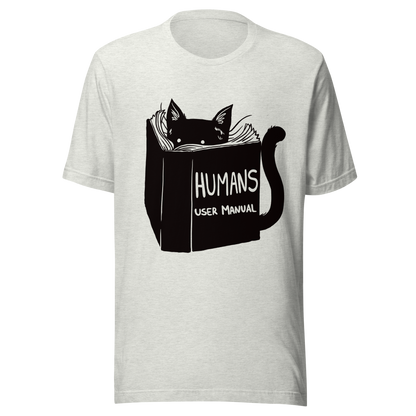 A kitten peeking out from behind a huge book titled "Humans: User Manual". This design plays on the idea that cats are trying to figure out how to control us. Perfect for cat lovers, book fans, and anyone who enjoys lighthearted humor in prints.