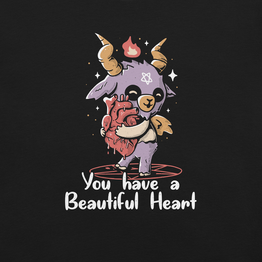 The design features a cute, cartoonish, anthropomorphic goat with big horns and a flame above its head, standing on a red pentagram. The goat has a star on its forehead and is hugging a large, anatomically correct human heart. The text below reads, 'You have a Beautiful Heart'. The image combines elements of occult symbolism with a playful, endearing aesthetic.