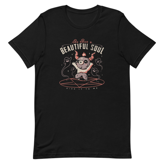 This design features a cute, cartoonish character with horns and a pentagram on its forehead, standing on a red circle with ghost-like figures surrounding it. Above the character, the text reads 'You have a beautiful soul,' and below, 'Give it to me.' The design contrasts dark and cute imagery with playful lettering.
