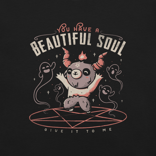 This design features a cute, cartoonish character with horns and a pentagram on its forehead, standing on a red circle with ghost-like figures surrounding it. Above the character, the text reads 'You have a beautiful soul,' and below, 'Give it to me.' The design contrasts dark and cute imagery with playful lettering.