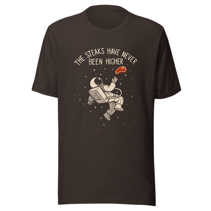 An astronaut floating through space with a small steak in front of him, paired with the phrase ‘The Steaks Have Never Been Higher’. A playful and humorous design that blends space exploration with a clever visual pun. Perfect for fans of witty wordplay and quirky art.