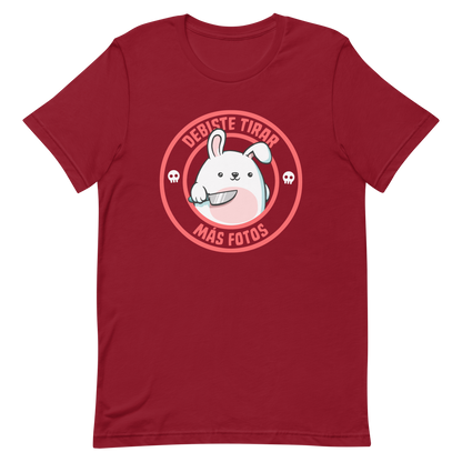 A cute white cartoon bunny with a pink belly stands holding a large kitchen knife in one paw. Surrounding the bunny is a red circular border with the words 'DEBISTE TIRAR MÁS FOTOS'. Small skull icons are on either side of the circle. The overall tone is a mix of adorable and ironic humor.