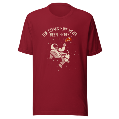 An astronaut floating through space with a small steak in front of him, paired with the phrase ‘The Steaks Have Never Been Higher’. A playful and humorous design that blends space exploration with a clever visual pun. Perfect for fans of witty wordplay and quirky art.