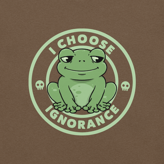 The image shows a cartoonish green frog with a sly smile, sitting with legs splayed out. Around it, the phrase 'I CHOOSE IGNORANCE' is written in bold letters. Two small skull designs are included, one on each side of the frog. The style is playful and ironic, blending elements of humor and rebellion.