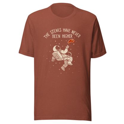 An astronaut floating through space with a small steak in front of him, paired with the phrase ‘The Steaks Have Never Been Higher’. A playful and humorous design that blends space exploration with a clever visual pun. Perfect for fans of witty wordplay and quirky art.
