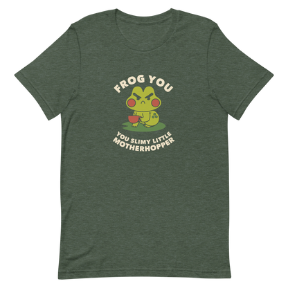 The design features a cartoonish green frog with exaggerated angry features, holding a teacup. The frog has round red cheeks. Above it, text says 'Frog You' and below, 'You Slimy Little Motherhopper'. The style is playful and humorous, reminiscent of cute comic art.