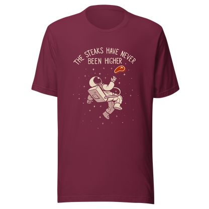 An astronaut floating through space with a small steak in front of him, paired with the phrase ‘The Steaks Have Never Been Higher’. A playful and humorous design that blends space exploration with a clever visual pun. Perfect for fans of witty wordplay and quirky art.