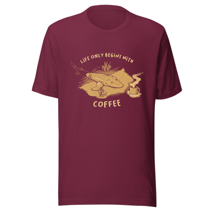 This funny illustration shows a tadpole evolving into a terrestrial creature while reaching for a cup of coffee. Paired with the phrase ‘Life Begins After Coffee Evolution’, the artwork humorously compares human evolution to our daily need for coffee.