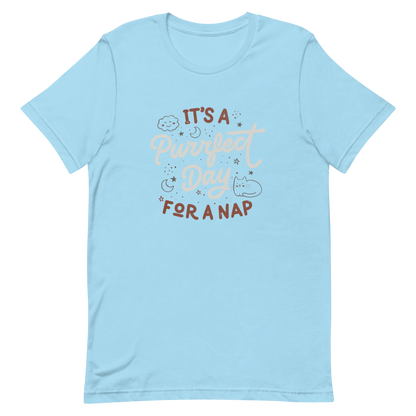 The artwork features the lettering "It's a Purrfect Day for a Nap" in a cute retro style, with a smiling cloud, stars, moons, and a relaxing kitten. This composition plays on the pun of "purrfect" and conveys all the charm of felines in their favorite moment: napping. Ideal for cat lovers, fans of funny phrases, and those who love to transform laziness into a lifestyle.