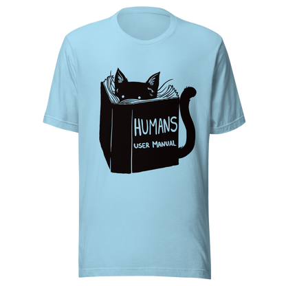A kitten peeking out from behind a huge book titled "Humans: User Manual". This design plays on the idea that cats are trying to figure out how to control us. Perfect for cat lovers, book fans, and anyone who enjoys lighthearted humor in prints.
