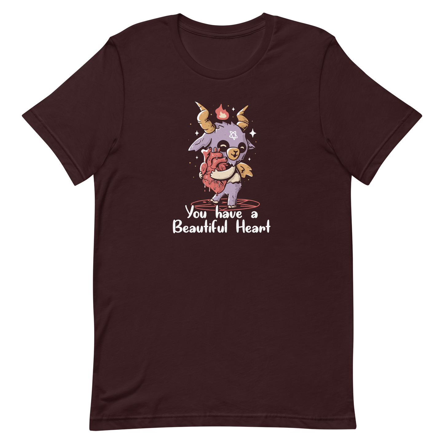 The design features a cute, cartoonish, anthropomorphic goat with big horns and a flame above its head, standing on a red pentagram. The goat has a star on its forehead and is hugging a large, anatomically correct human heart. The text below reads, 'You have a Beautiful Heart'. The image combines elements of occult symbolism with a playful, endearing aesthetic.