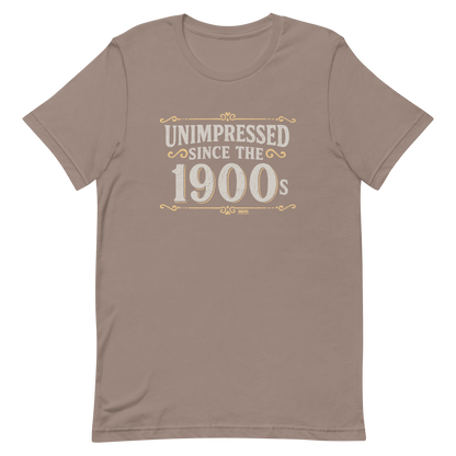 Vintage-style graphic with the phrase “Unimpressed Since the 1900s” in bold distressed lettering, decorated with ornate flourishes and a retro color palette.