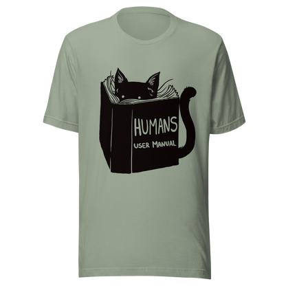 A kitten peeking out from behind a huge book titled "Humans: User Manual". This design plays on the idea that cats are trying to figure out how to control us. Perfect for cat lovers, book fans, and anyone who enjoys lighthearted humor in prints.