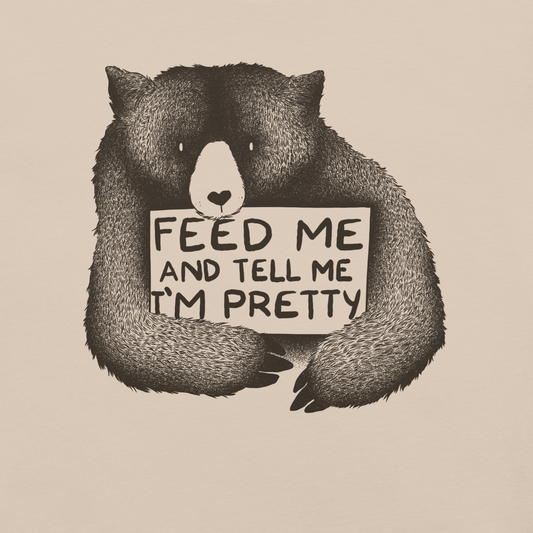 This drawing is of a cute, cartoon-style bear holding a sign with a heart-shaped nose and simple, expressive eyes. The sign reads, 'Feed me and tell me I'm pretty' in a handwritten, playful font. The bear's fur is detailed with fine, textured lines, giving it a cozy, endearing look. The drawing has a monochrome, black-and-white color scheme