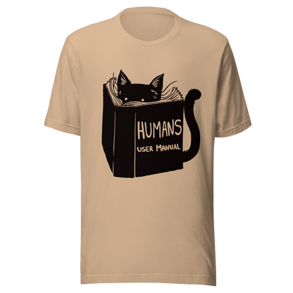 A kitten peeking out from behind a huge book titled "Humans: User Manual". This design plays on the idea that cats are trying to figure out how to control us. Perfect for cat lovers, book fans, and anyone who enjoys lighthearted humor in prints.