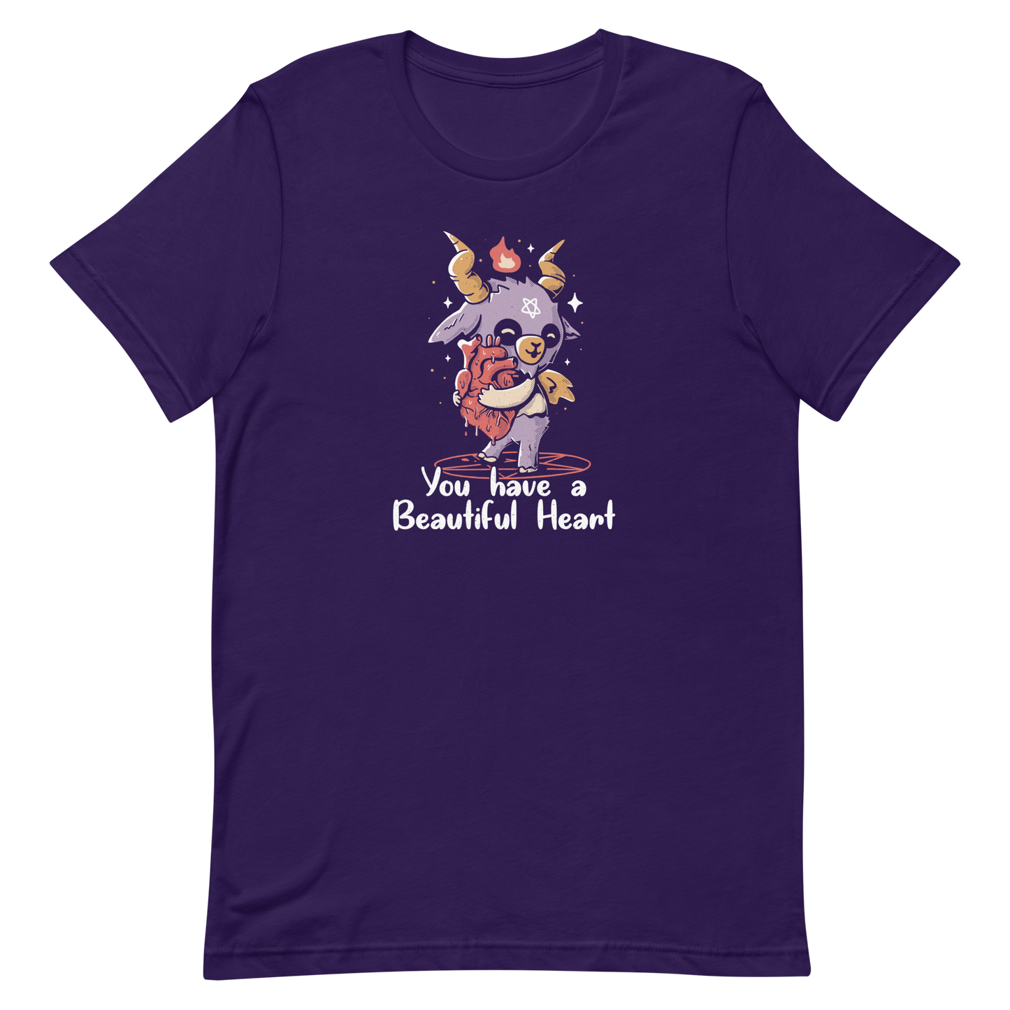 The design features a cute, cartoonish, anthropomorphic goat with big horns and a flame above its head, standing on a red pentagram. The goat has a star on its forehead and is hugging a large, anatomically correct human heart. The text below reads, 'You have a Beautiful Heart'. The image combines elements of occult symbolism with a playful, endearing aesthetic.