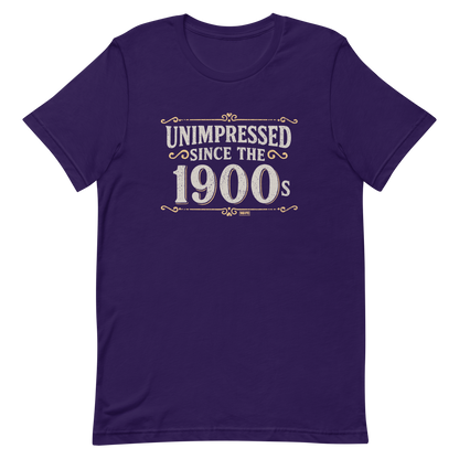 Vintage-style graphic with the phrase “Unimpressed Since the 1900s” in bold distressed lettering, decorated with ornate flourishes and a retro color palette.