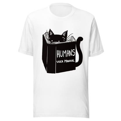 A kitten peeking out from behind a huge book titled "Humans: User Manual". This design plays on the idea that cats are trying to figure out how to control us. Perfect for cat lovers, book fans, and anyone who enjoys lighthearted humor in prints.